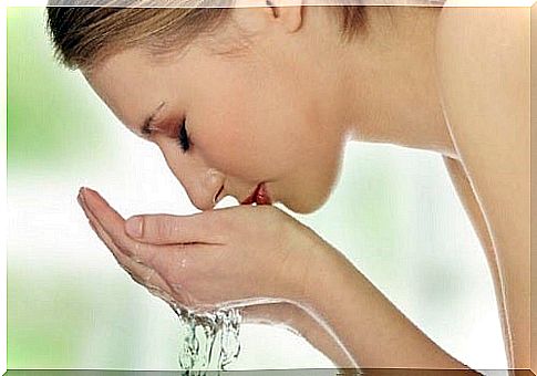 A woman rinsing her face with water for natural makeup