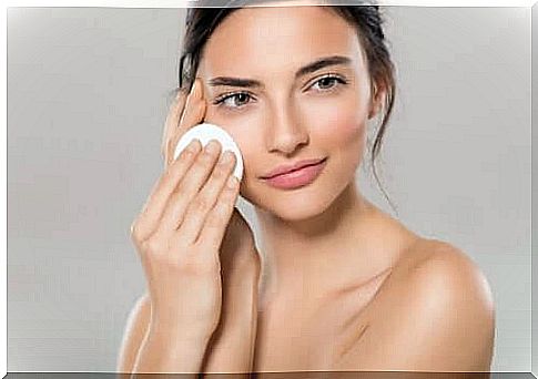 A woman who cleans her face with a cotton pad before natural makeup