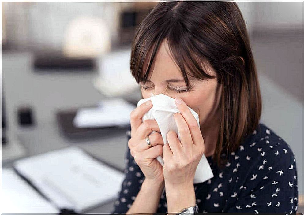 A woman blowing her nose due to allergic reactions